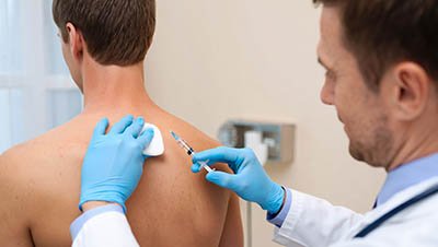 Врач держит в руке шприц и ватку